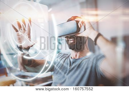 Concept of digital screen, connection and interfaces.Beraded hipster enjoyingvirtual reality glasses in modern design home studio.Smartphone use with VR goggles headset.Horizontal, flare, blurred