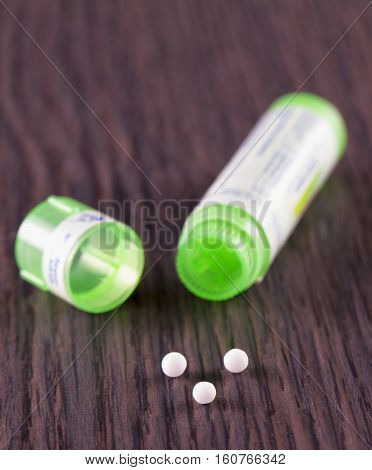 Homeopathic pills over wooden table vertical image