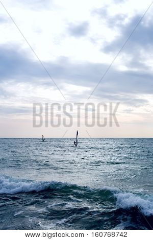 Group of windsurfers on boards in wavy sea. Lifestyle and sport completition concept. Group of people. Fun and leisure activity. Vertical composition.