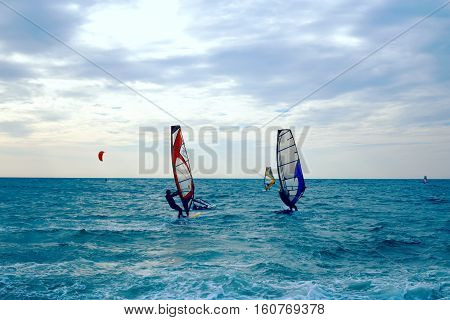 Group of windsurfers on boards in wavy sea. Lifestyle and sport completition concept. Group of people. Fun and leisure activity.