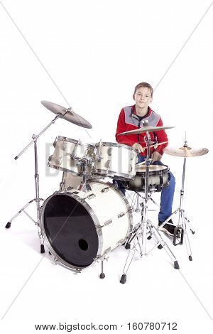 teenage caucasian boy plays drums in studio with white background