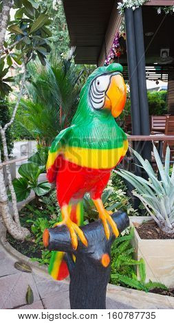 Parrot toy in the garden. Parrot on the perch in the garden.