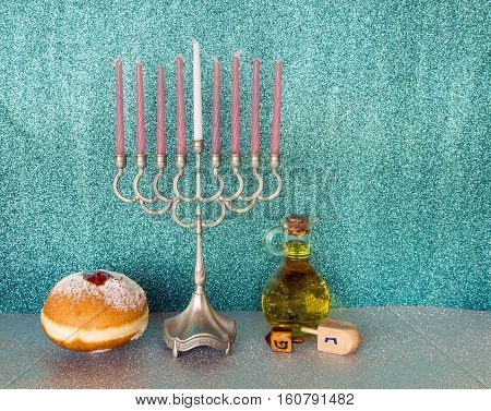 Jewish menorah with candles, sweet donuts wooden dreidels and jar of olive oil are traditional symbols for Hanukkah holiday