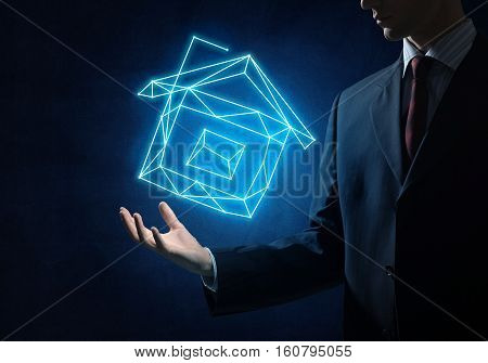 Close of buinessman holding in palm glowing house symbol