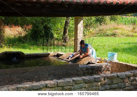 MELIDE SPAIN - AUGUST 14: A woman washes her clothes in the wash house on August 14 2016