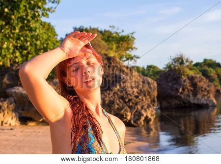 Sunstroke at the beach. Young woman with heatstroke. Girl with sun stroke during beach day. Dangerous sun. Keeping health on vacation.