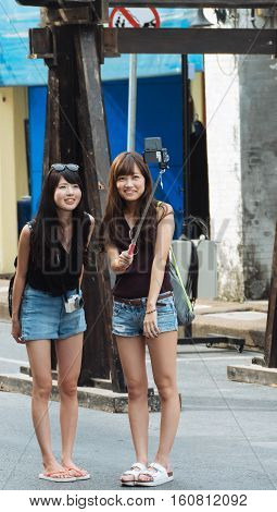 PHUKET THAILAND SEPTEMBER 27: Tourists selfie at the walking street among old building Chino Portuguese style street of Phuket town in Phuket Thailand on September 27 2016.