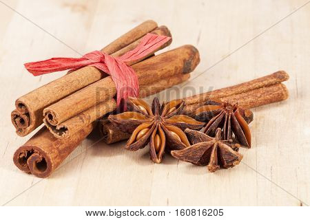Cinnamon sticks and anise stars on wooden plank.