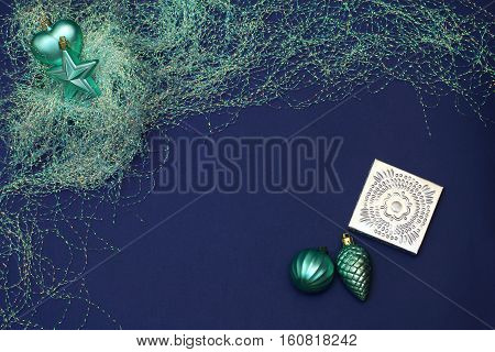 Christmas/New year composition of toys and tinsel, turquoise color. Magic composition. Dark blue background, top view, flat lay,copy space
