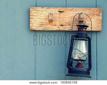 Burning kerosene lamp hang on the wooden wall. Home decoration by old lamp in vinage style.