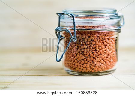 Glass Jar Of Dried Red Lentils On Wood Table