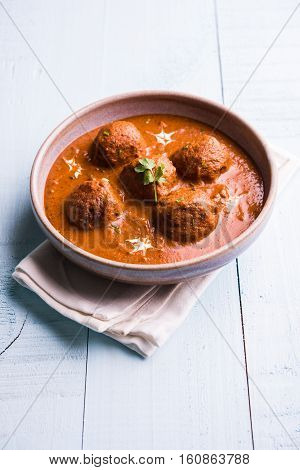 malai kofta curry - classic North Indian dish. vegetarian alternative to meatballs served with tandoori roti or indian bread and green salad, selective focus