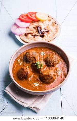 malai kofta curry - classic North Indian dish. vegetarian alternative to meatballs served with tandoori roti or indian bread and green salad, selective focus