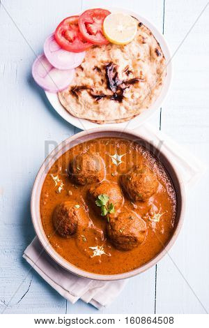 malai kofta curry - classic North Indian dish. vegetarian alternative to meatballs served with tandoori roti or indian bread and green salad, selective focus