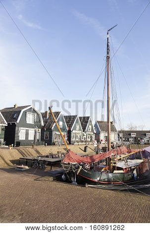 Marken, Netherlands, 22 november 2016: old sailing vessel in harbor of dutch village Marken and old wooden houses