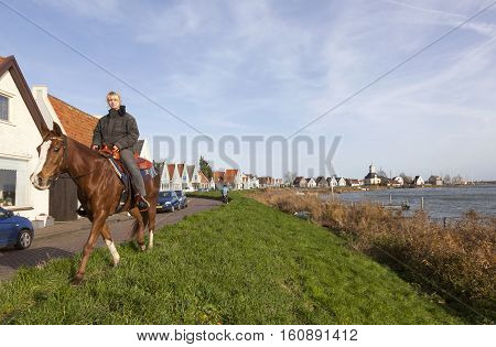 Durgerdam, Netherlands, 22 november 2016: girl on horseback on durgerdam dike near amsterdam in the netherlands