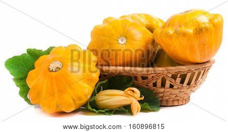 yellow pattypan squash with leaf and flower in a wicker basket isolated on white background.