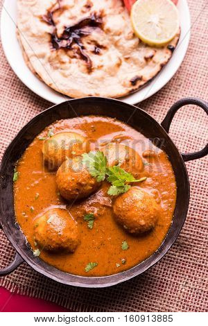 Freshly cooked spicy potato curry in frying pan or Hot and spicy Dum aloo served with tandoori roti or naan or indian bread or chapati and green salad, selective focus