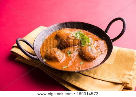 Freshly cooked spicy potato curry in frying pan or Hot and spicy Dum aloo served with tandoori roti or naan or indian bread or chapati and green salad, selective focus