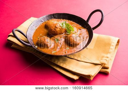 Freshly cooked spicy potato curry in frying pan or Hot and spicy Dum aloo served with tandoori roti or naan or indian bread or chapati and green salad, selective focus