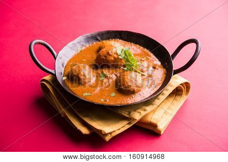 Freshly cooked spicy potato curry in frying pan or Hot and spicy Dum aloo served with tandoori roti or naan or indian bread or chapati and green salad, selective focus