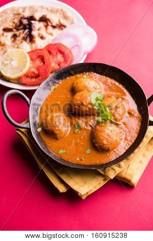 Freshly cooked spicy potato curry in frying pan or Hot and spicy Dum aloo served with tandoori roti or naan or indian bread or chapati and green salad, selective focus