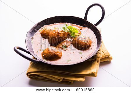 Freshly cooked spicy potato curry in frying pan or Hot and spicy Dum aloo served with tandoori roti or naan or indian bread or chapati and green salad, selective focus