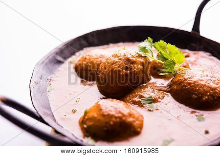 Freshly cooked spicy potato curry in frying pan or Hot and spicy Dum aloo served with tandoori roti or naan or indian bread or chapati and green salad, selective focus