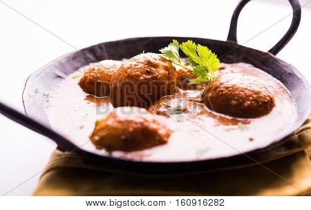 Freshly cooked spicy potato curry in frying pan or Hot and spicy Dum aloo served with tandoori roti or naan or indian bread or chapati and green salad, selective focus