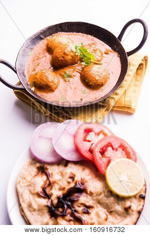 Freshly cooked spicy potato curry in frying pan or Hot and spicy Dum aloo served with tandoori roti or naan or indian bread or chapati and green salad, selective focus