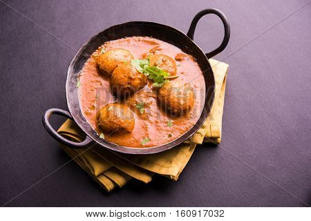Freshly cooked spicy potato curry in frying pan or Hot and spicy Dum aloo served with tandoori roti or naan or indian bread or chapati and green salad, selective focus