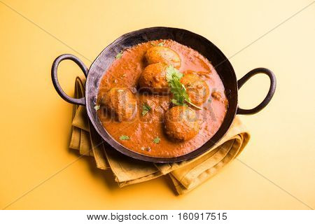 Freshly cooked spicy potato curry in frying pan or Hot and spicy Dum aloo served with tandoori roti or naan or indian bread or chapati and green salad, selective focus