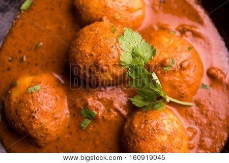 Freshly cooked spicy potato curry in frying pan or Hot and spicy Dum aloo served with tandoori roti or naan or indian bread or chapati and green salad, selective focus