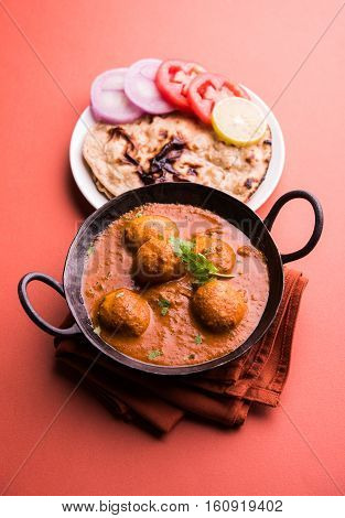 Freshly cooked spicy potato curry in frying pan or Hot and spicy Dum aloo served with tandoori roti or naan or indian bread or chapati and green salad, selective focus
