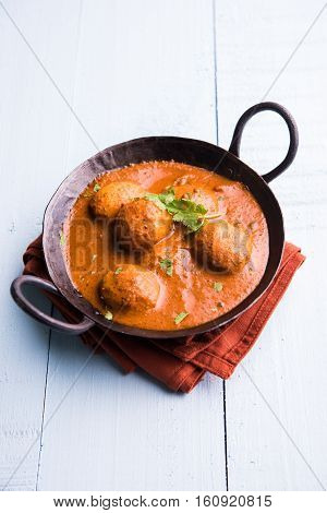 Freshly cooked spicy potato curry in frying pan or Hot and spicy Dum aloo served with tandoori roti or naan or indian bread or chapati and green salad, selective focus