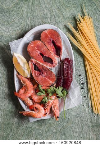 Fresh red fish shrimp and spaghetti - cooking ingredients. On wooden background top view
