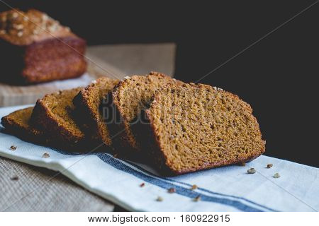 Pumpkin spice bread and bread slices with pecans on a striped towel