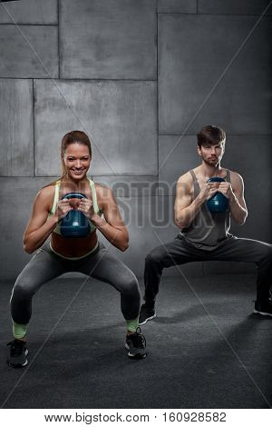 Young people training in gym, using kettlebells.