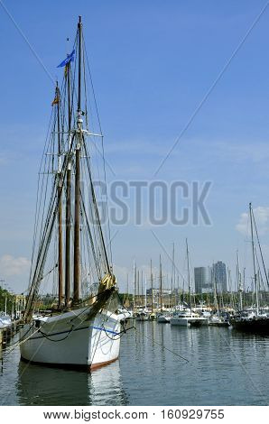 Yacht moored near Moll d`Espanya. Vertical view to big white yacht on the background of small boats moored near Aquarium Barcelona