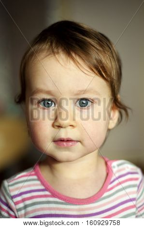 Portrait of white baby girl with grey eyes. Curious baby on blurred background. mother`s love. Concept of calmness, care, innocence.