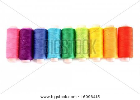 Pile of coloured bobbins of lurex thread isolated on white