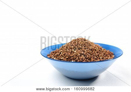 Buckwheat grains in Blue bowl from above isolated on white background. On right side