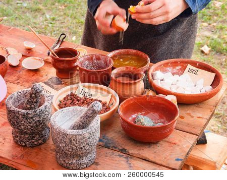 Woman Dressed In Medieval Clothes Making Paints From Natural Ingredients. Annual Festival Times And 