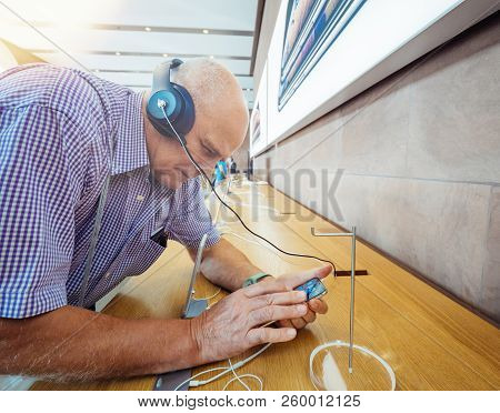 Strasbourg, France - Sep 21, 2018: Side View Of Curious Senior Man Testing Apple Beats By Dr Dre Hea