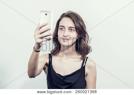 Beautiful Young Girl Holding A Phone. Makes Photos, Selfies