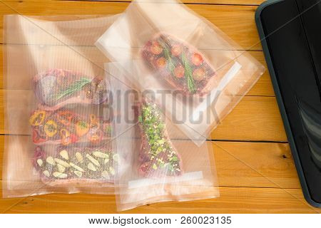 Three Vacuum Packed Bags Of Flat Iron Steaks Alongside The Sealer Machine Each With A Different Seas