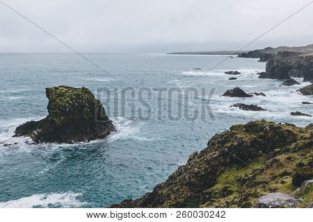 Dramatic Shot Of Rocks In Blue Ocean In Arnarstapi, Iceland On Stormy Day
