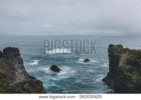 Aerial View Of Cliffs In Front Of Blue Ocean In Arnarstapi, Iceland On Cloudy Day