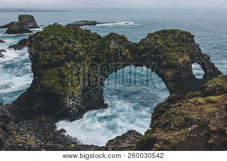 Dramatic Mossy Cliffs In Front Of Blue Ocean In Arnarstapi, Iceland On Cloudy Day