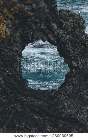 View Of Ocean Waves Through Hole In Cliff, Arnarstapi, Iceland